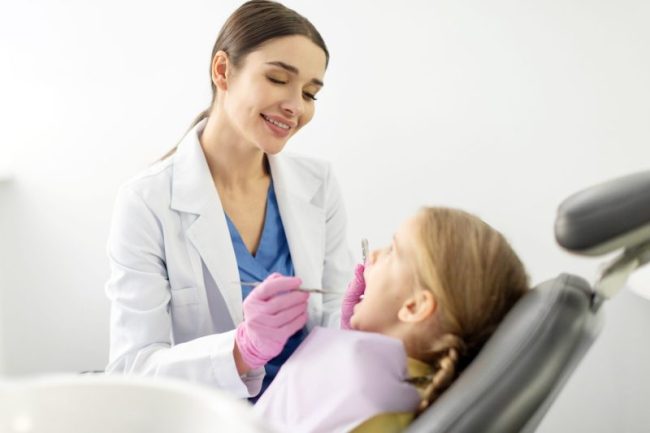 Young,Woman,Dentist,Treating,Kid,Tooth,,Little,Girl,Sitting,In dentist taylorsville ut