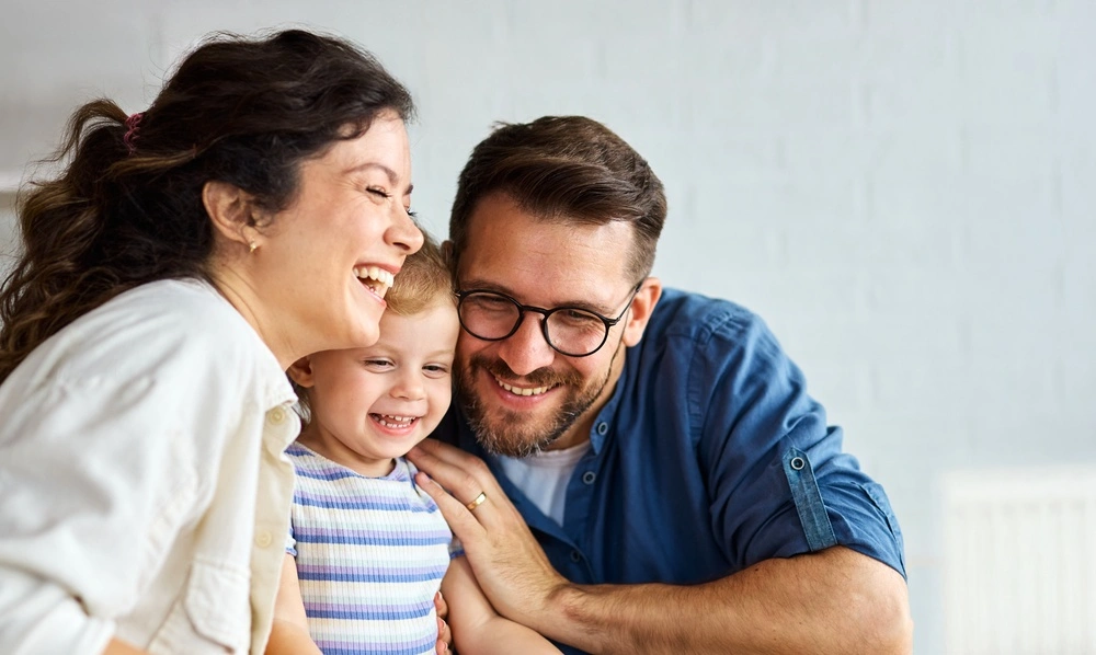 Parents smiling with their toddler son, illustrating fluoride treatments for children