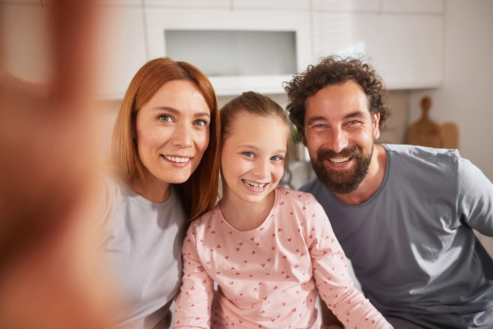 Family of three smiling together in their kitchen, illustrating preventative dental care