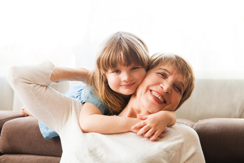 Grandmother and granddaughter hugging on a sofa, for the families in the areas we serve